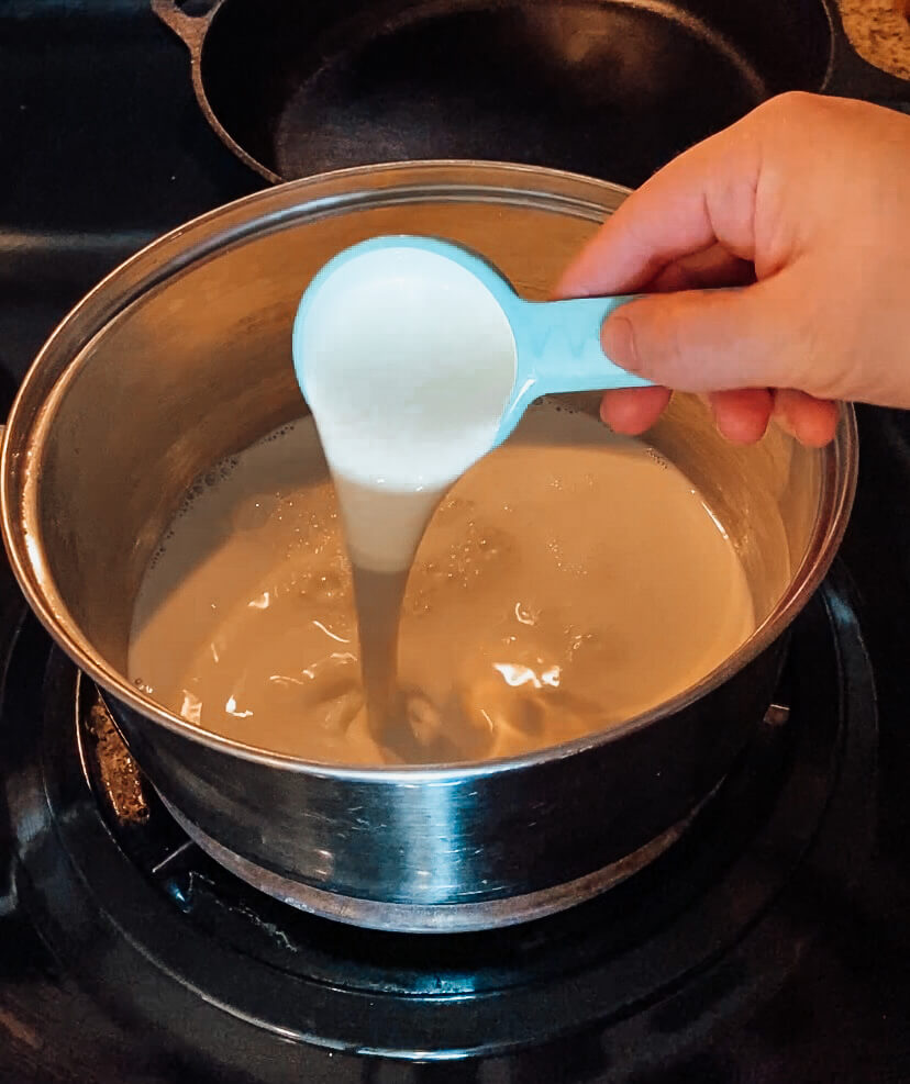 hand pouring heavy whipping cream into a sauce pan