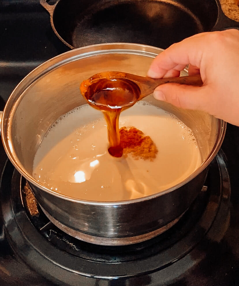 hand pouring maple syrup into a saucepan