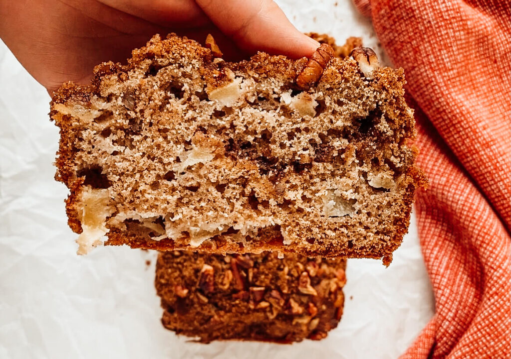hand holding piece of cinnamon apple pecan bread