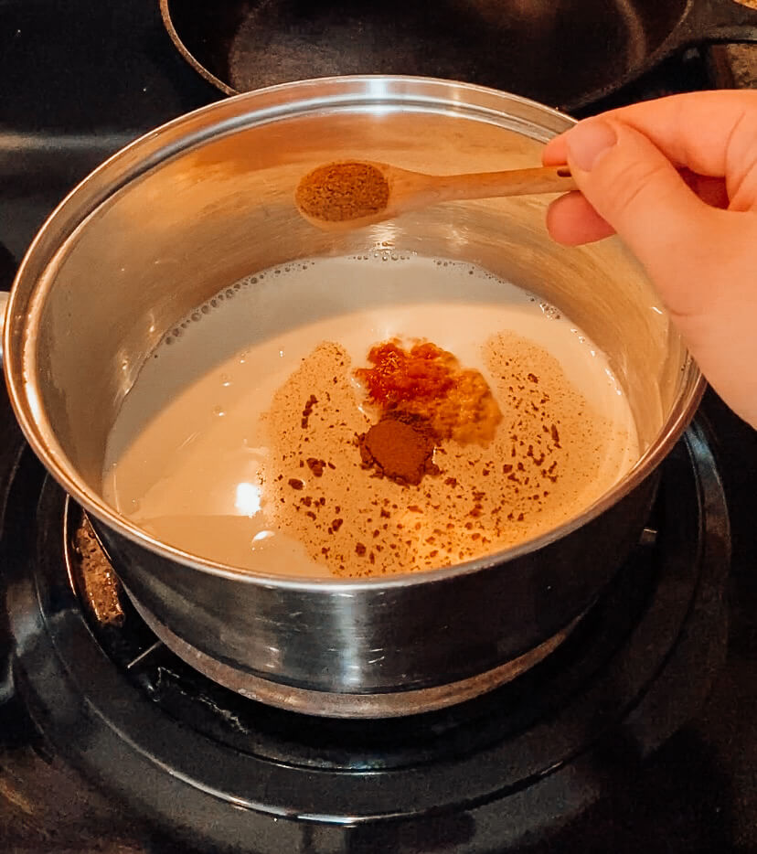 hand pouring cinnamon into sauce pan